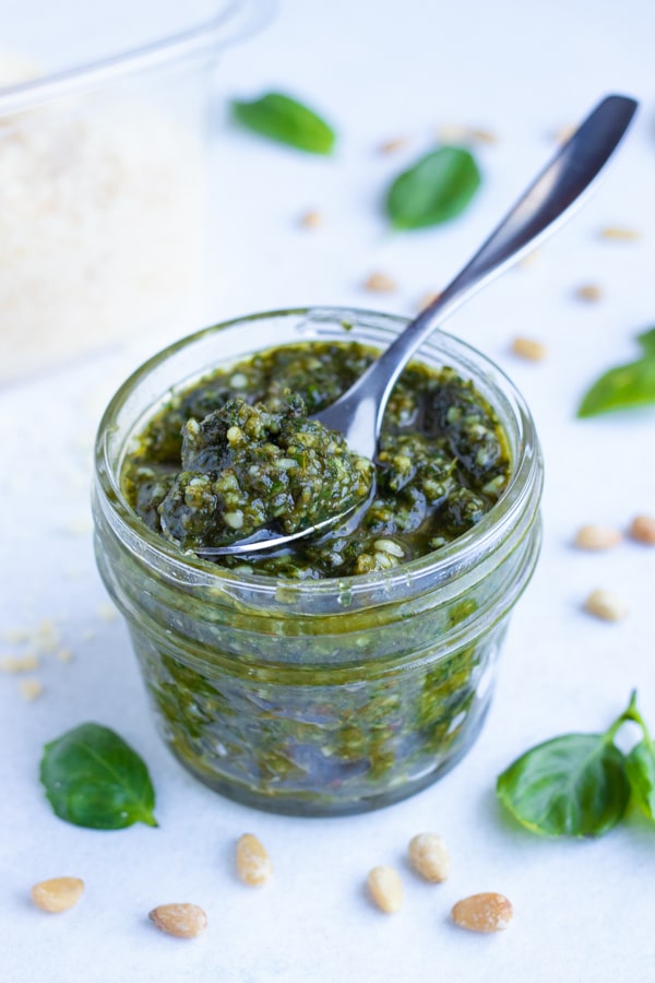 A small mason jar holds fresh, basil pesto sauce that can be used on chicken or pasta dishes.