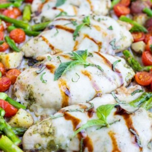 Potatoes are cooked first then followed by tomatoes, chicken, and asparagus in this easy meal prep sheet pan chicken recipe.