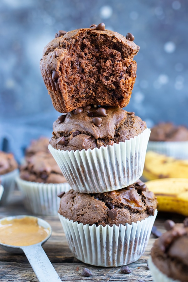Vegan Chocolate Banana Muffins are stacked on top of each other on the counter.