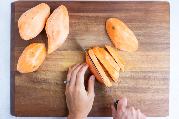 Sweet potatoes being cut into fries to be baked in the oven.