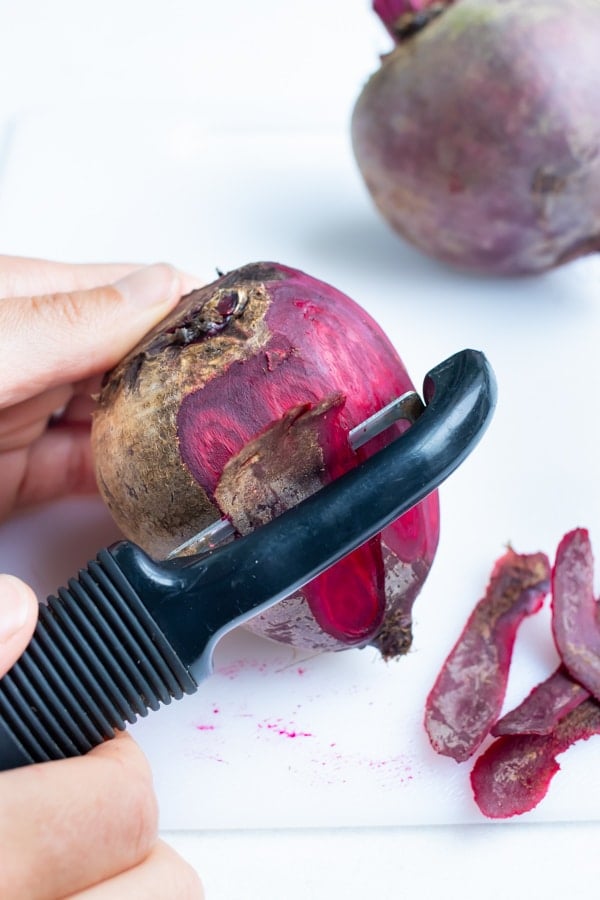 Whole beets are peeled with a vegetable peeler before being roasted in the oven.