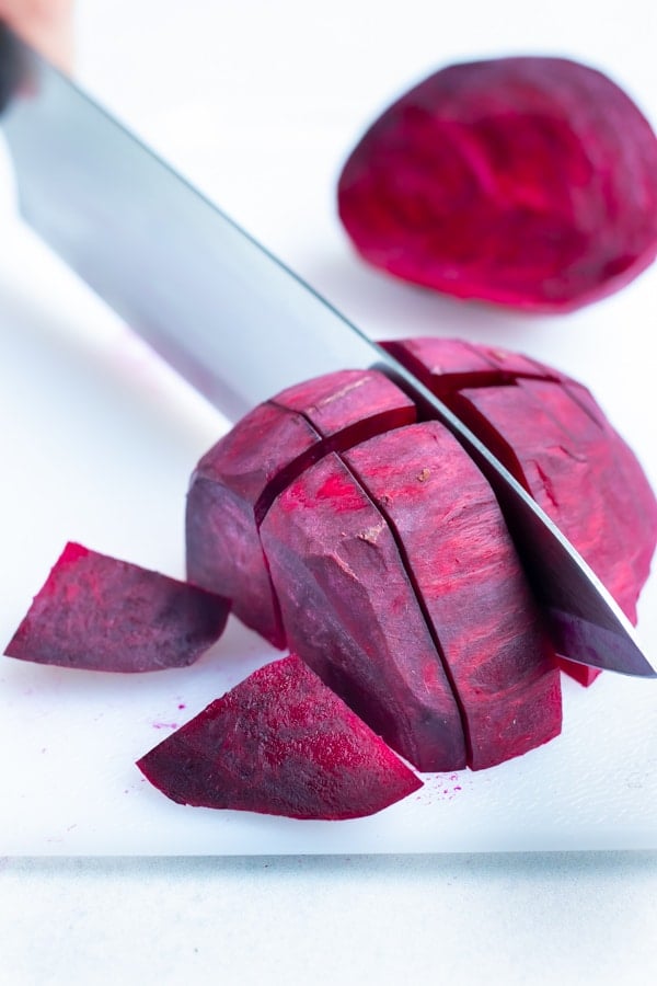 Fresh whole beets are chopped before roasting in the oven.