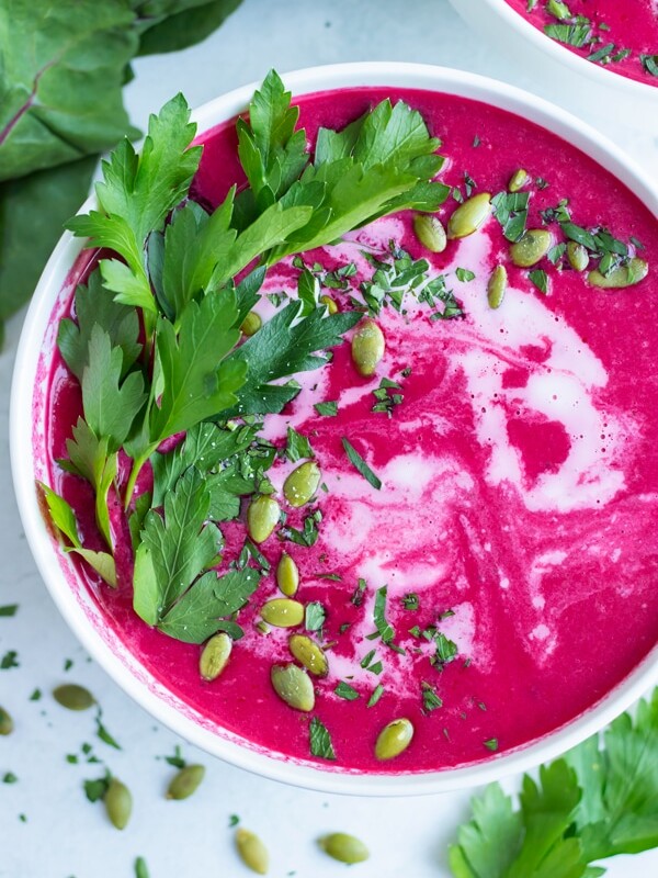 A creamy, vegan, and whole30 beet soup with pumpkin seeds in a white bowl.