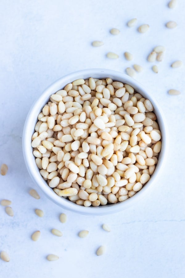 Roasted pine nuts are placed in a bowl before being used in pesto, pasta, or salads.
