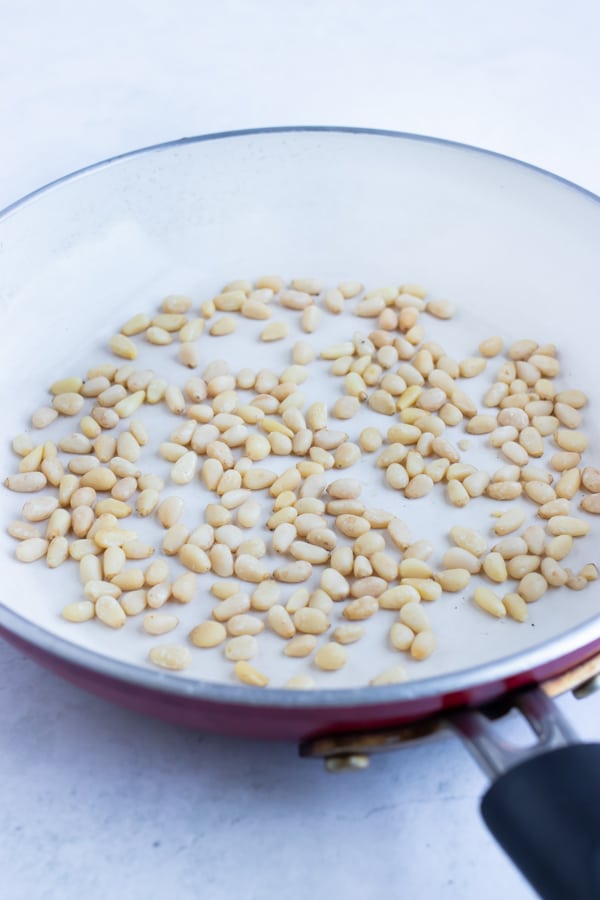 Use a skillet or pan to toast pine nuts on the stove.