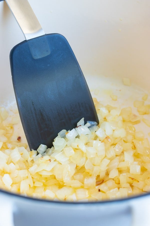 Diced onions are sautéed in a skillet before using in this sweet potato chili.