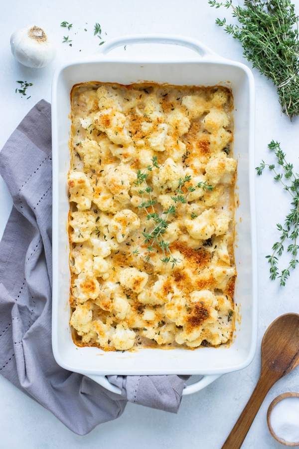 Baked cauliflower gratin is top with fresh herbs for a keto friendly side.