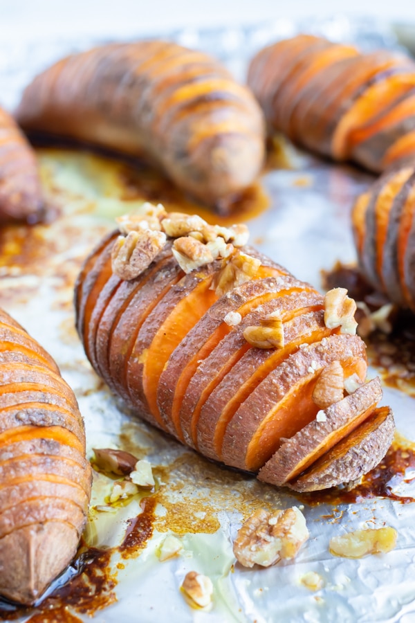 Baked sweet potatoes are topped with chopped pecans and put back in the oven.