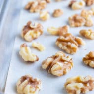 Walnuts are placed on a lined baking sheet and toasted in the oven.