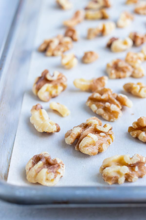 Walnuts are placed on a lined baking sheet and toasted in the oven.