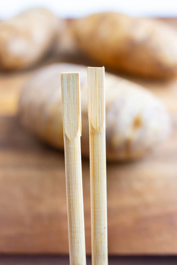 Square chopsticks are used to help cut the potato.
