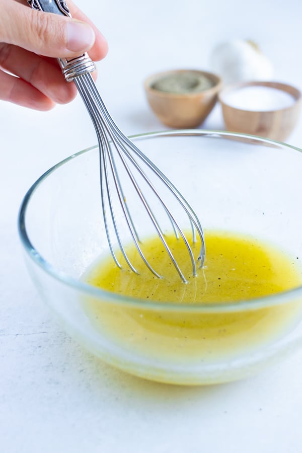 Melted butter and oil are combined in a bowl with garlic, salt, and pepper.