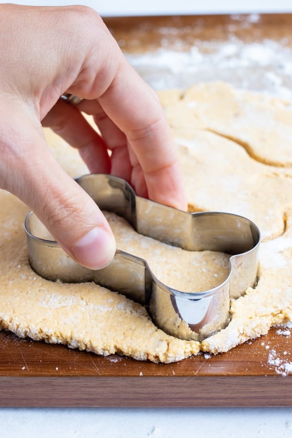 Peanut butter pumpkin dog treats are cut into bone shapes before baking.