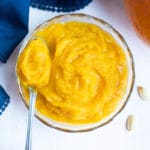 Homemade pumpkin puree is kept on the counter in a glass bowl before using in recipes.