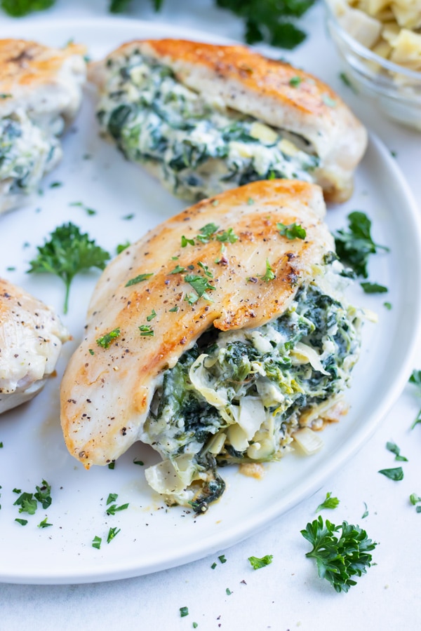 Chicken stuffed with a homemade spinach artichoke filling is served on a plate for dinner.