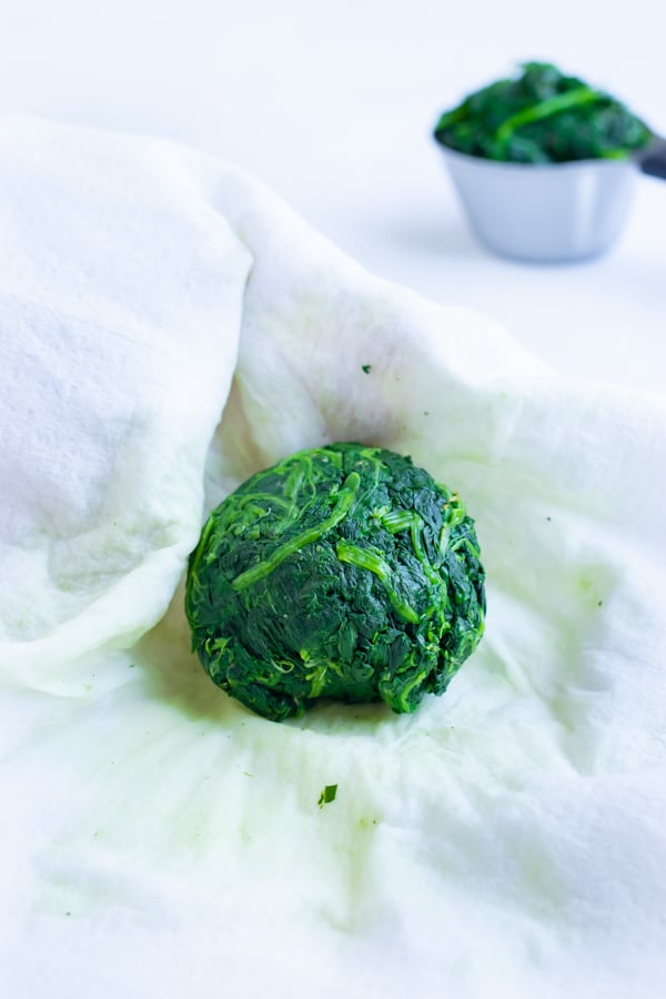Moisture is squeezed from the spinach before measuring and adding to the filling recipe.