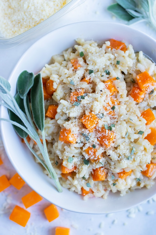 Roasted butternut squash risotto with sage is served in a white bowl on the counter.