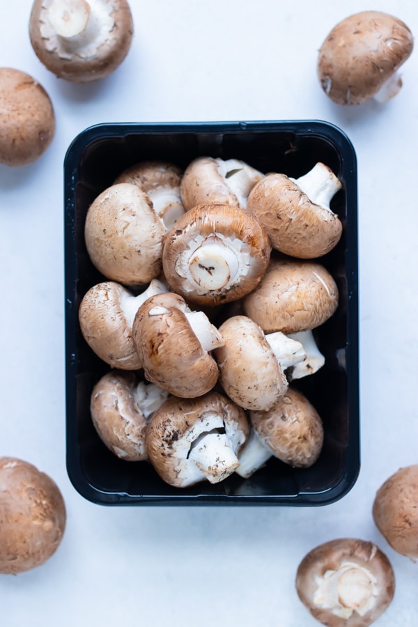Mushrooms are shown in a container on a counter.