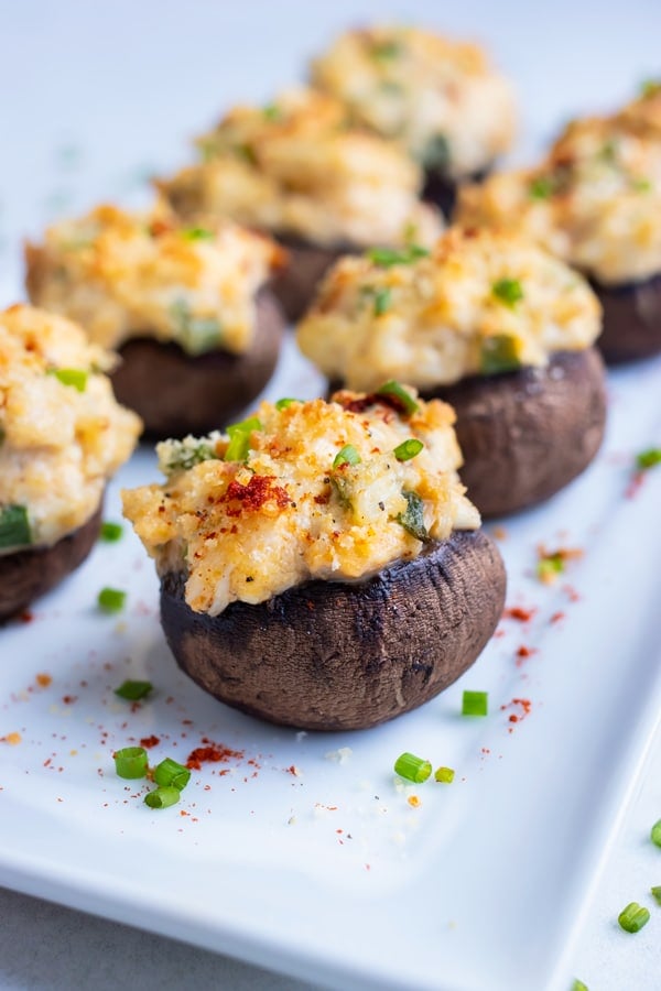 Creamy crab stuffed mushrooms are served on a white tray.