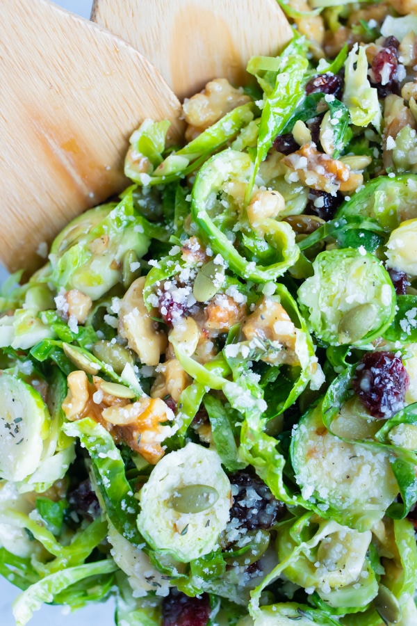Raw Brussels sprouts and other ingredients are tossed with the dressing until combined.