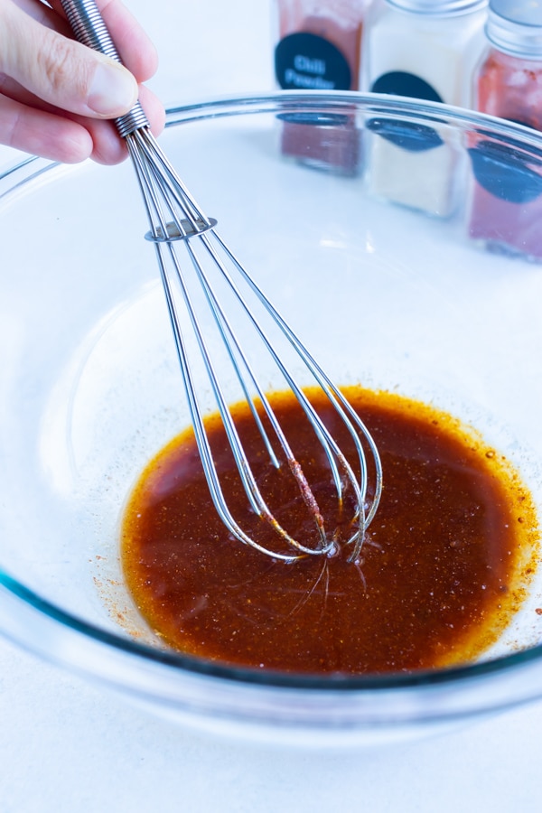 Maple syrup, melted butter, and seasonings are whisked together in a bowl.