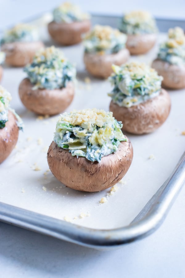 Stuffed mushrooms are placed on a baking sheet and baked in the oven.