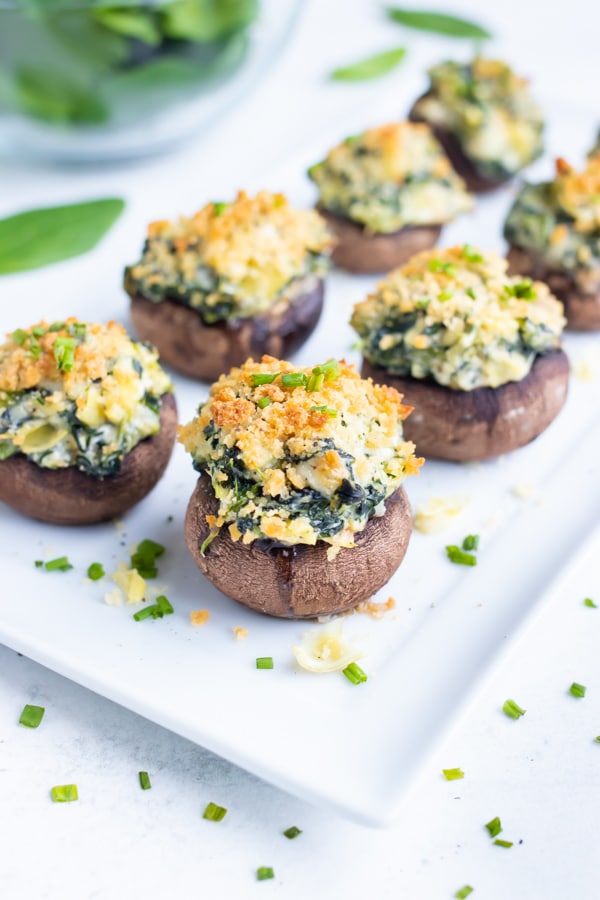 Crisp and golden brown spinach artichoke mushrooms are served on a platter with chives.