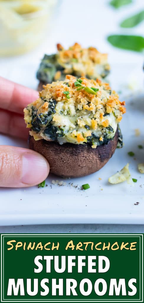 Spinach artichoke stuffed mushrooms are picked up for a finger-food appetizer.