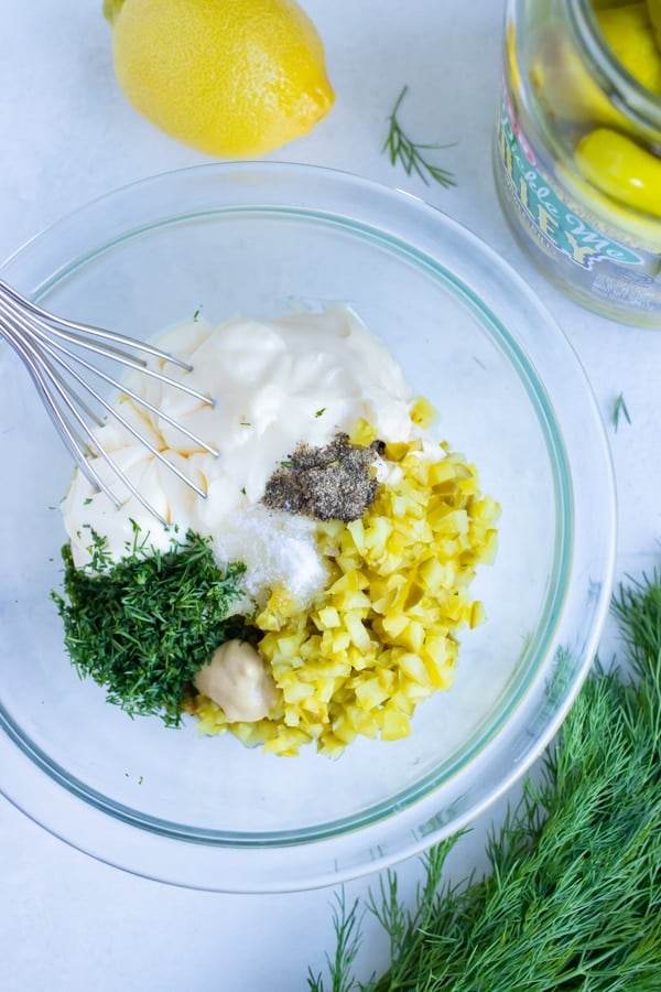 Tartar sauce ingredients are combined in a glass bowl.