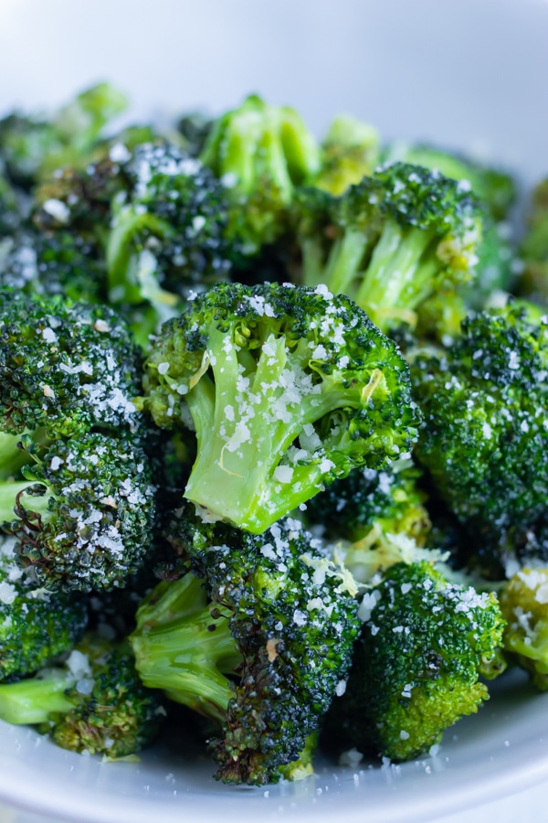 Healthy roasted broccoli is topped with lemon juice and parmesan cheese.