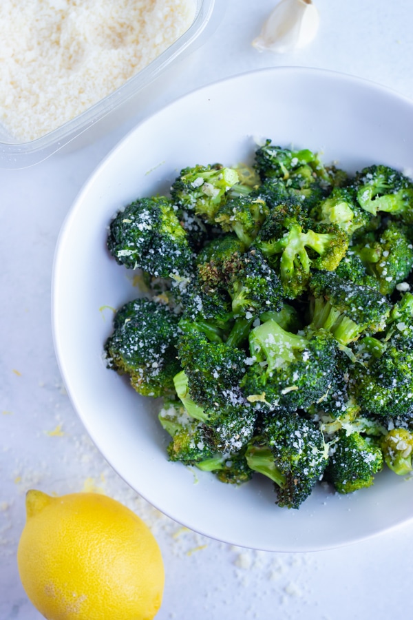 Air fryer Parmesan garlic broccoli is served with lemon zest on a white plate.