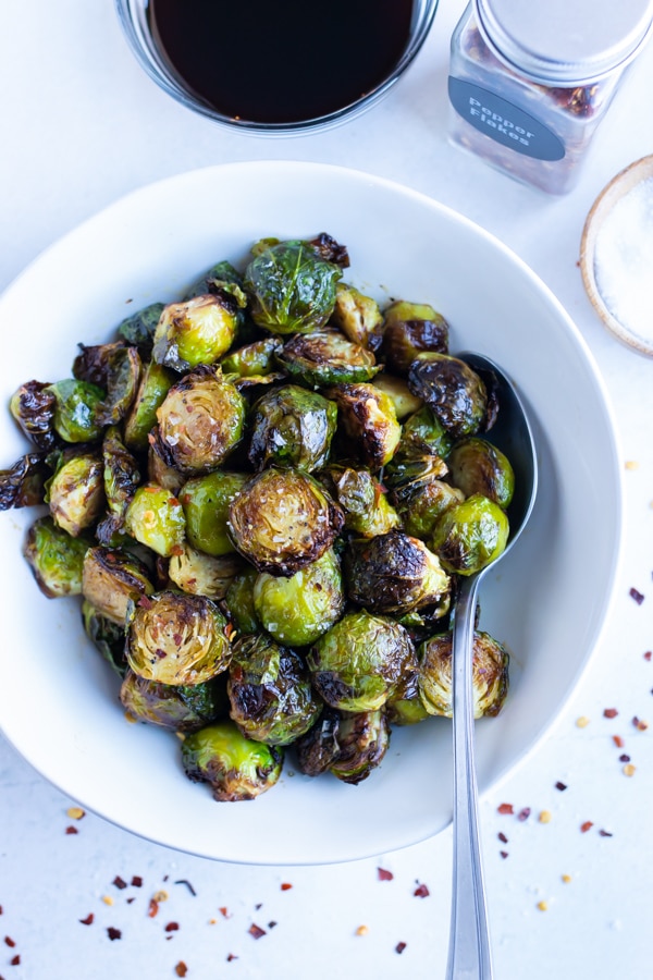 Air fryer brussels sprouts are served in white bowl for a vegetarian dish.