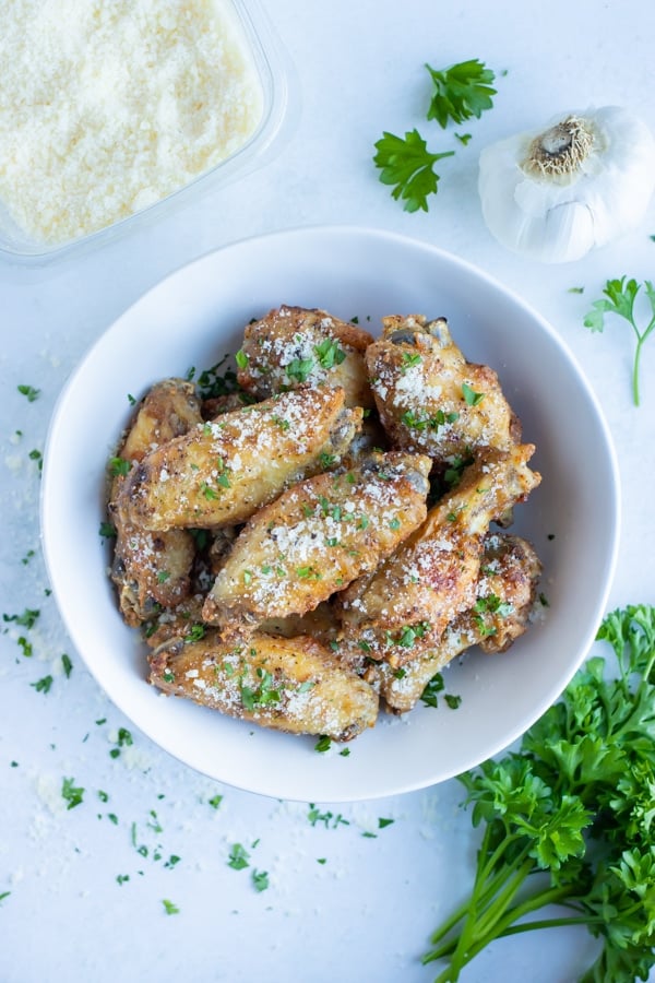 Air fryer chicken wings are served in a white bowl for healthy party food.