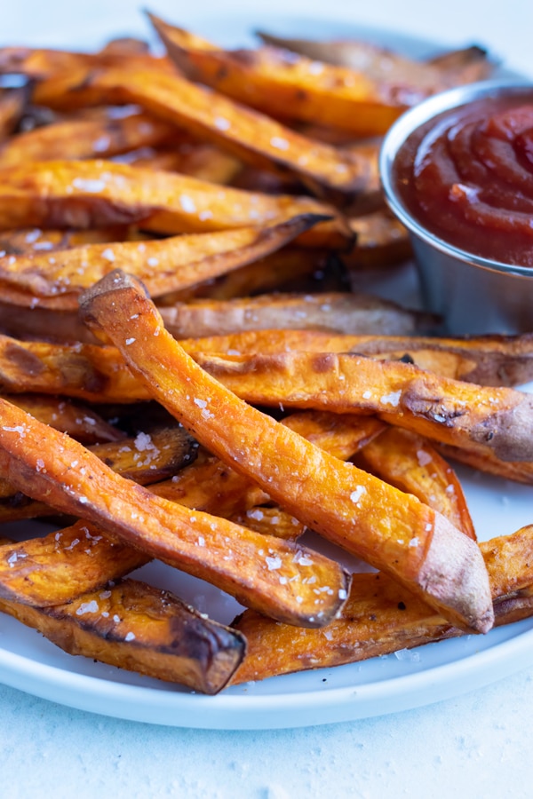 Crispy and healthy sweet potato fries made in your air fryer are served with ketchup.