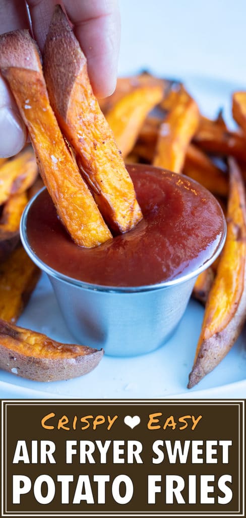 Two sweet potato fries are dipped into ketchup.