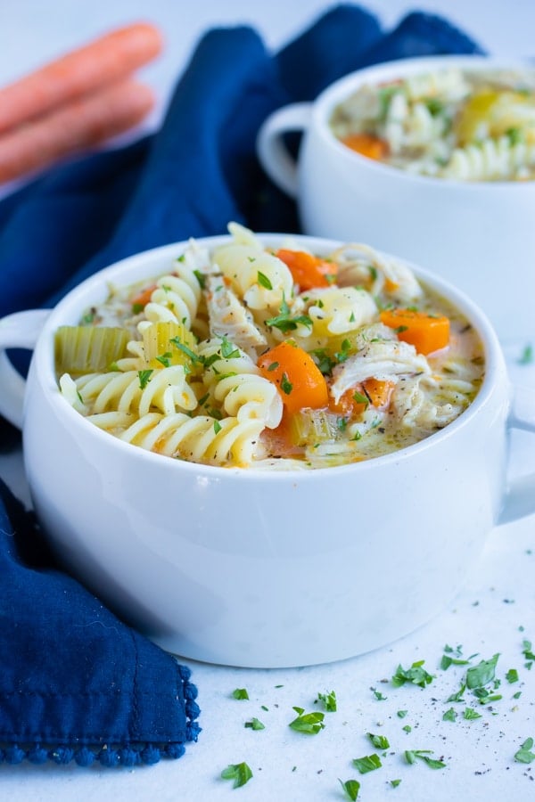 Two bowls of dairy-free, gluten-free chicken noodle soup are served on the counter.