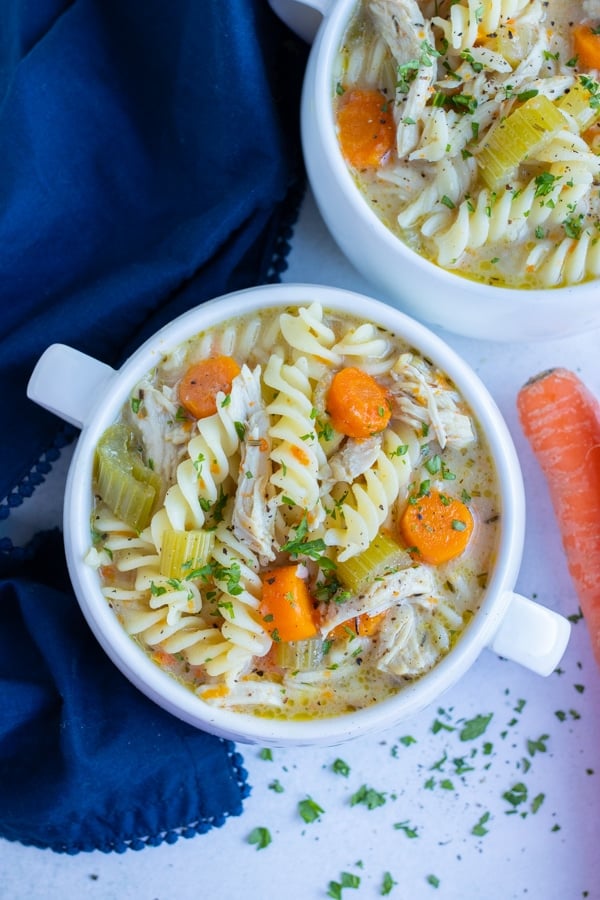 Two bowls of chicken noodle soup are served for a kid friendly meal.