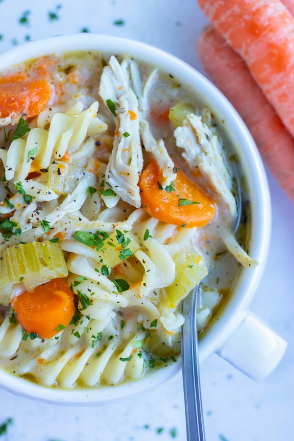 Easy instant pot chicken noodle soup, loaded with pasta, is eaten with a metal spoon.