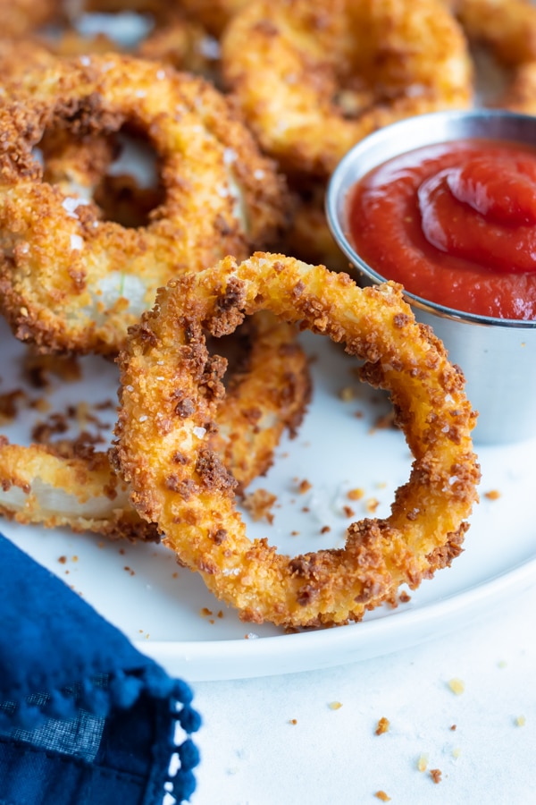 Healthy onion rings are enjoyed with ketchup for a game day appetizer.