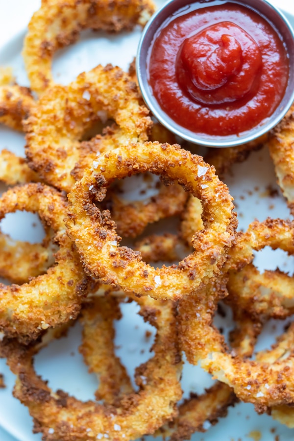 Air Fryer onion rings are served with ketchup for a party appetizer.