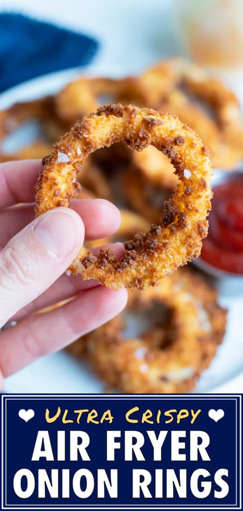 An onion ring is lifted up by a hand for a close up picture.