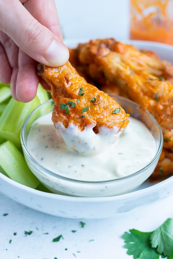 A low-carb buffalo chicken wing is dipped in ranch dressing.