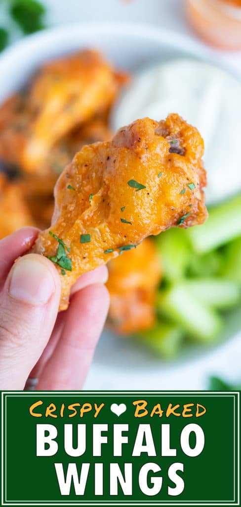 Healthy baked chicken wings are held by a hand.