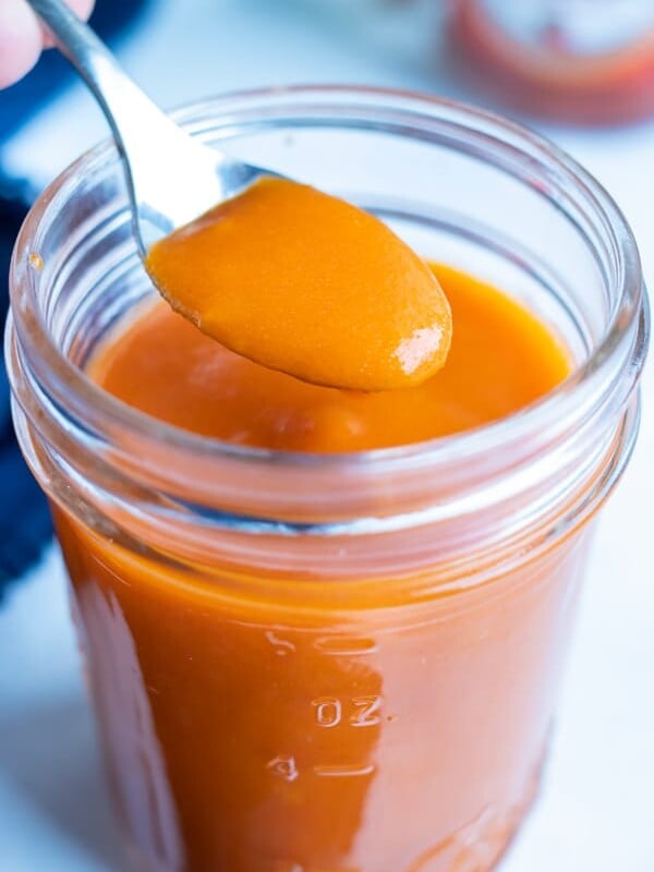 Spicy buffalo sauce is lifted up with a spoon before putting on wings.