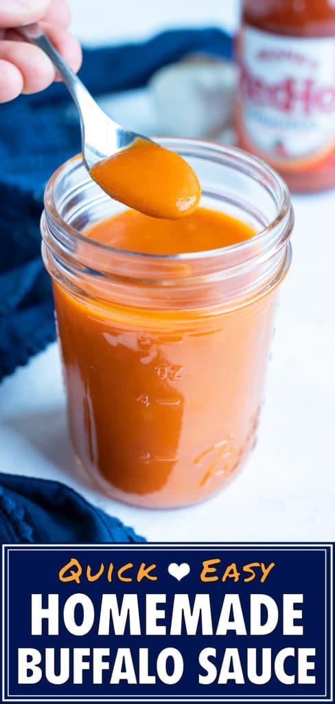 Buffalo sauce is lifted out of a mason jar with a spoon.