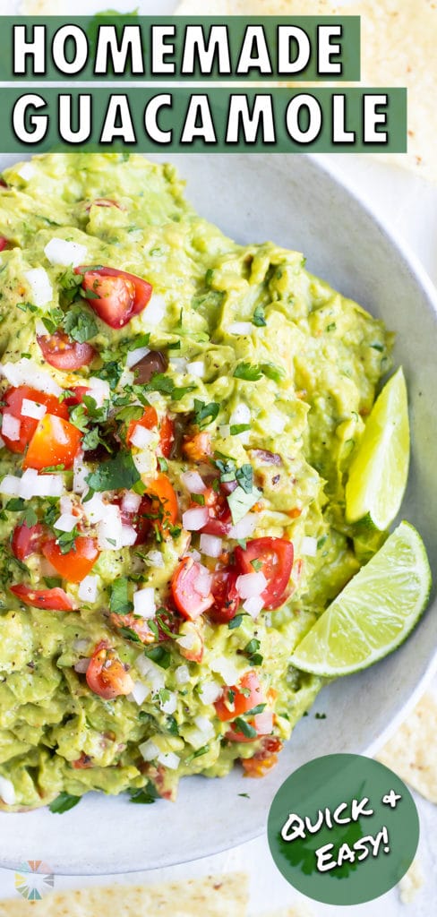 A white bowl full of a simple guacamole recipe with limes, tomatoes, and onions to garnish.