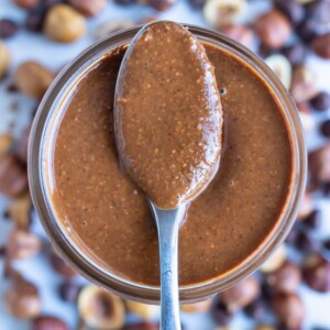 Vegan nutella is shown in a mason jar with a spoon.