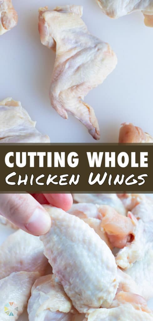 A wingette is lifted up by a hand out of a pile of cut chicken wings.