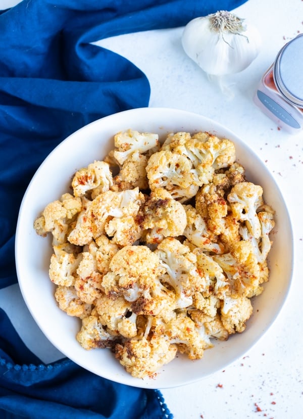 Seasoned air fryer cauliflower is served in a white bowl.