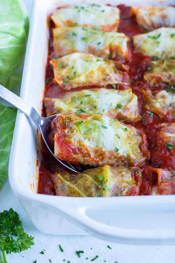 Cabbage rolls are lifted out with a spoon for dinner.